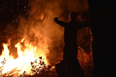 Silhouette man standing against fire crackers at night