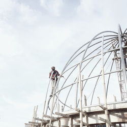 Low angle view of man working at construction site against sky