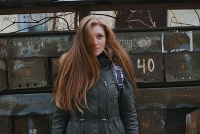 Portrait of young woman standing against wall