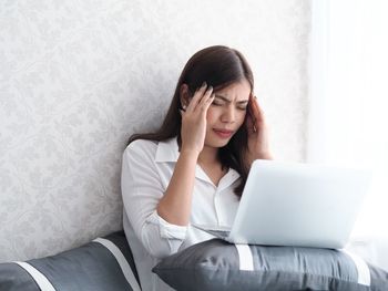 Young woman using phone while sitting on sofa