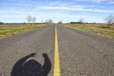 Shadow of child on road against sky