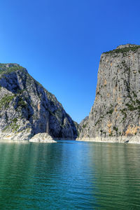 Scenic view of sea and mountains against clear blue sky