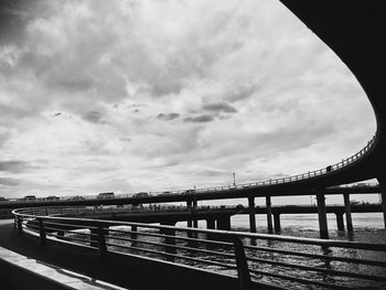 Footbridge over river in city against sky