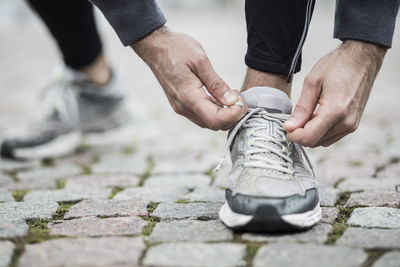 Low section of man tying lace of sports shoe