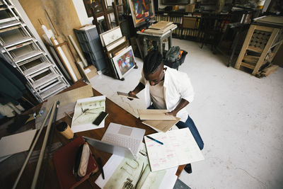 Directly above shot of male architect examining wooden swatch while sitting in workshop