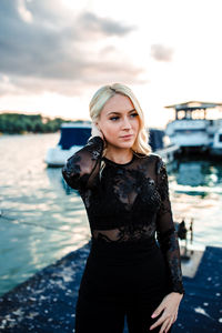 Portrait of beautiful young woman standing against sky