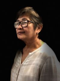 Close-up of senior woman wearing eyeglasses against black background