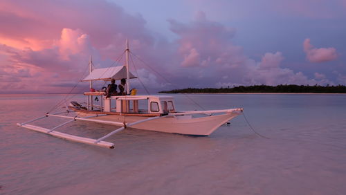 Sailboat moored in sea against sky during sunset