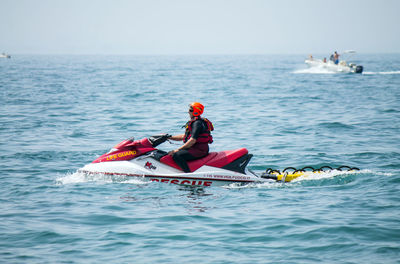 People on boat in sea against sky