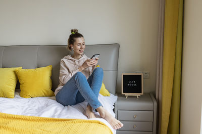 Young woman using mobile phone while sitting at home