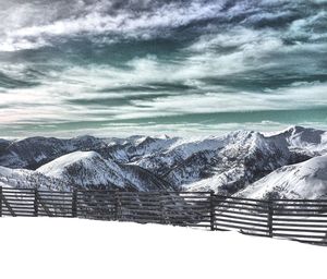Scenic view of snow covered mountains against cloudy sky