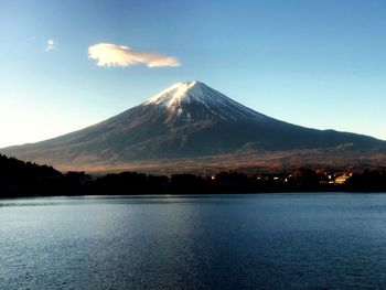 Scenic view of lake by snowcapped mountain against sky