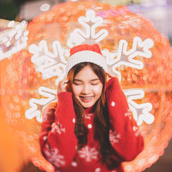 Portrait of smiling young woman standing against christmas
