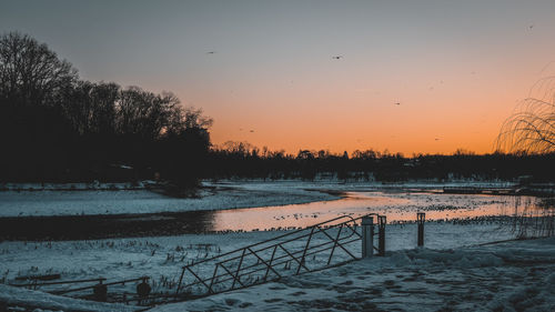 Scenic view of lake against orange sky during winter