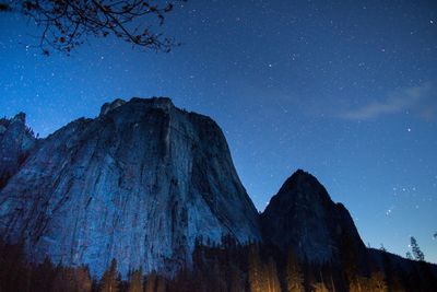 Low angle view of rocky mountains against star field at yosemite national park