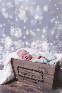 Cute baby boy sleeping in crate at home