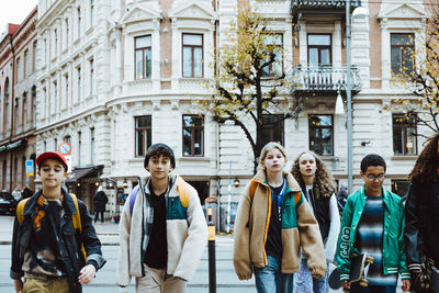 Multiracial boys and girls walking on road against building in city