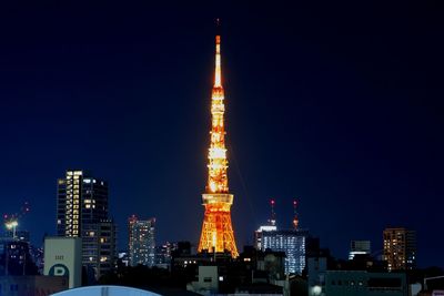 Illuminated tower in city against sky at night