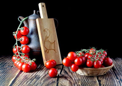 Close-up of tomatoes in basket on table against black background