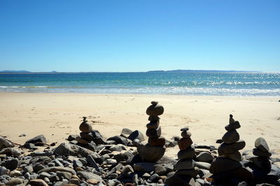 Stacked stones at beach on sunny day