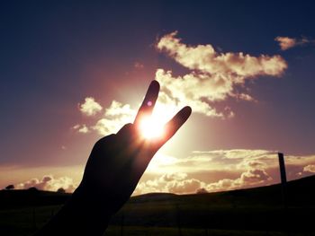 Close-up of hand holding sun against sky