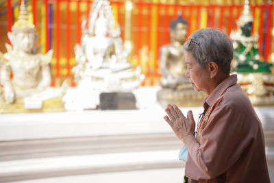 Side view of woman praying at temple