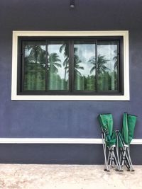 The folding bed is placed on the wall of the house, with a shadow of coconut trees in the mirror