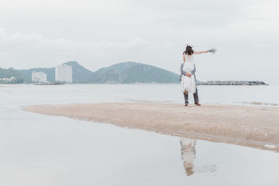 Rear view of woman standing on beach against sky