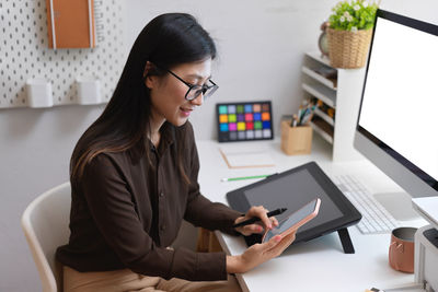 Woman using mobile phone while sitting on table