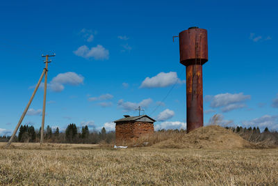 Windmill on field against blue sky