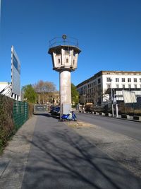 Street amidst buildings against clear blue sky watchtower of the berlin wall