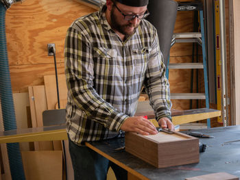 A woodworker checking for square on the box he is building in his workshop