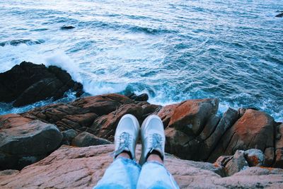 Low section of man standing on rock by sea