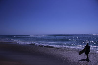 Woman walking on beach against clear sky