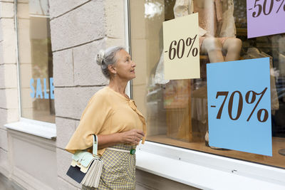 Smiling senior woman looking in shop window of a boutique