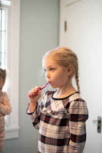 Portrait of cute girl standing against wall