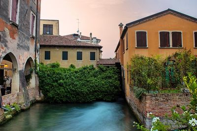 Canal amidst buildings in town against sky