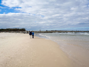 People walking on beach against sky