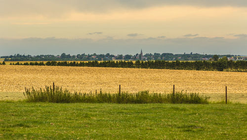 French countryside landscape with a small village in the distance and big fields in the foreground.