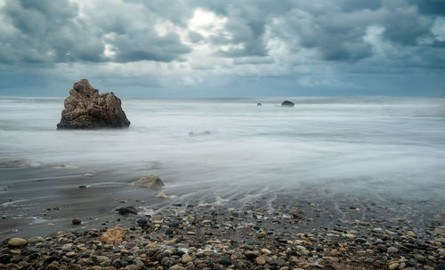 Scenic view of rocks on beach against sky