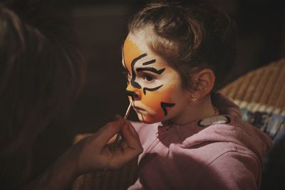 Cropped image of artist painting face of cute girl