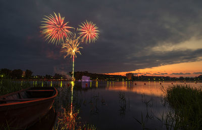 Firework display over lake against sky at night