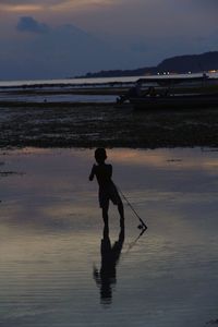 Silhouette man standing on beach against sky during sunset