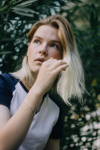 Close-up portrait of young woman against trees