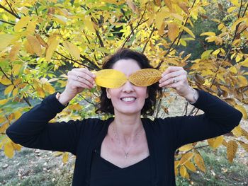 Portrait of a smiling young woman holding autumn leaf