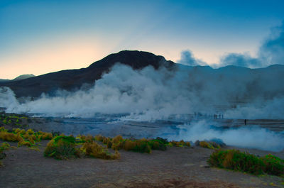 Smoke emitting from mountain against sky