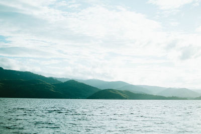 Scenic view of sea by mountains against sky