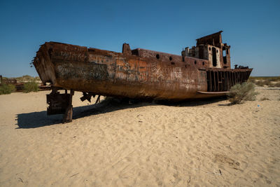 Abandoned boat on beach against clear sky