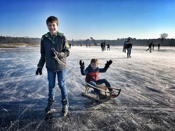 Portrait of siblings on ice rink against sky