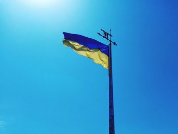 Low angle view of flag against clear blue sky